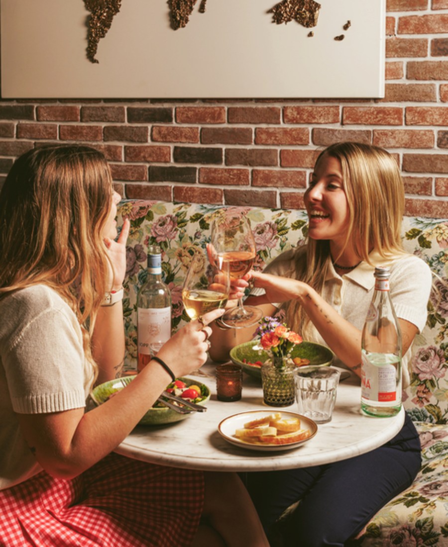 Two friends laughing over a glass of wine at Sospiro